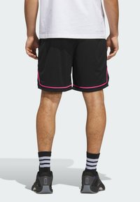 Mustat urheilushortsit, joissa on vaaleanpunaiset reunat ja sivuyksityiskohdat, valmistettu kevyistä materiaaleista. Yhdistetty mustiin kenkiin ja raidallisiin sukkiin.