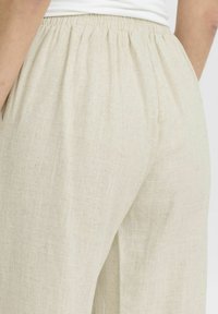 Lichtbeige linnen broeken met een elastische tailleband en een gestructureerde afwerking. Bevat zijzakken en een losse pasvorm voor comfort.