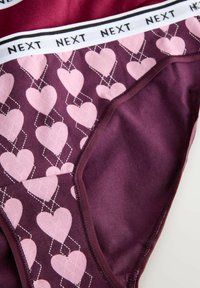Burgundi női alsónemű fehér "NEXT" logós derékszallaggal. Rózsaszín szív mintázattal, fehér varrással körülvéve. Puha tapintású, rugalmas anyag.