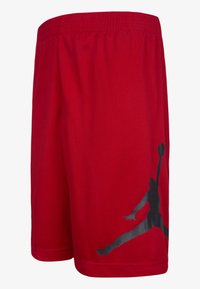 Shorts deportivos rojos hechos de tela ligera, con una cinturilla elástica y un gran logo negro de Jumpman en el lado izquierdo.
