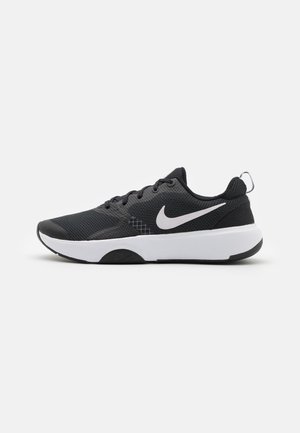 Chaussure de course Nike noire avec logo swoosh blanc, lacets noirs et semelle blanche épaisse sur un fond gris clair uni.