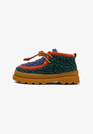 Shoe de tecido verde texturizado com detalhes em laranja e azul, sola de borracha e atacadores coloridos. Apresenta um colar acolchoado e detalhes costurados.