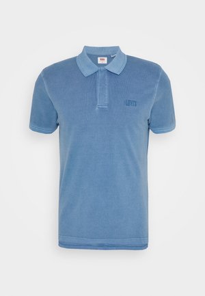 Polo bleu en coton, avec col, manches courtes et logo brodé sur la poitrine gauche. Texture lisse partout.