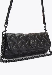 Borsa a tracolla nera in pelle trapuntata con tracolla a catena. Presenta un tessuto testurizzato, accessori in metallo e un emblema decorativo sul davanti.