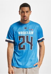 Blå sportsdrakt med svart "24" og "WROCŁAW" trykt. Har korte ermer med hvite og mørkeblå striper. Lett tekstur av stoff.