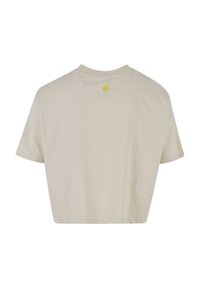 Cropped beige t-shirt with short sleeves, made of soft fabric. Features a small yellow logo on the upper back. Simple and minimalist design.