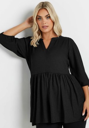 Tunic nera con tessuto strutturato, dotata di un orlo plissettato e scollo a V. Ha maniche a trequarti e una vestibilità comoda.