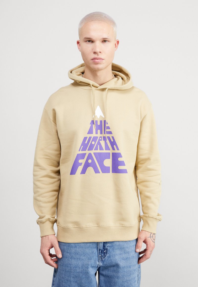 Sudadera con capucha de color beige con un logo triangular morado que dice "THE NORTH FACE". Tejido suave, corte estándar y puños acanalados.