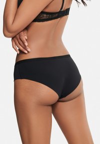 Czarne hipsterskie majtki wykonane z gładkiego materiału, z elastycznym paskiem bez widocznego śladu i minimalnym krojem.