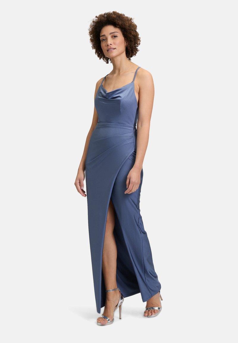 Satin blauwe avondjurk met een sjaalkraag, dunne bandjes en een hoge split tot aan de dij. Model draagt zilveren hakken, die een zachte textuur en elegant ontwerp laten zien.