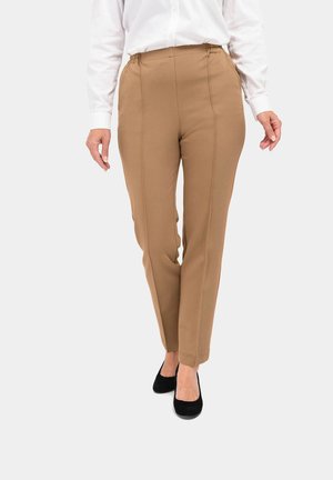 Beige Hose mit elastischem Bund, geradem Bein und seitlichen Nahtdetails, kombiniert mit schwarzen Ballerinas und einem weißen Hemd mit Kragen.