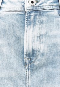 Close-up of light blue denim jeans showing the button, zipper area, and detailed stitching.