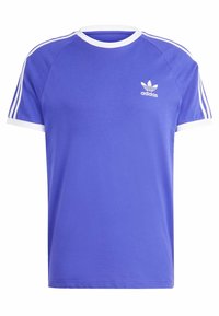 Fioletowa bawełniana koszulka z białymi wykończeniami, z okrągłym dekoltem i trzema białymi paskami na każdym ramieniu. Logo Adidas w białym kolorze na klatce piersiowej.