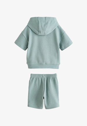 Vaaleansininen teksturoitu lyhythihainen huppari, jossa on huppu, ja siihen sopivat joustovyötäröshortsit, jotka on valmistettu hengittävästä kankaasta.