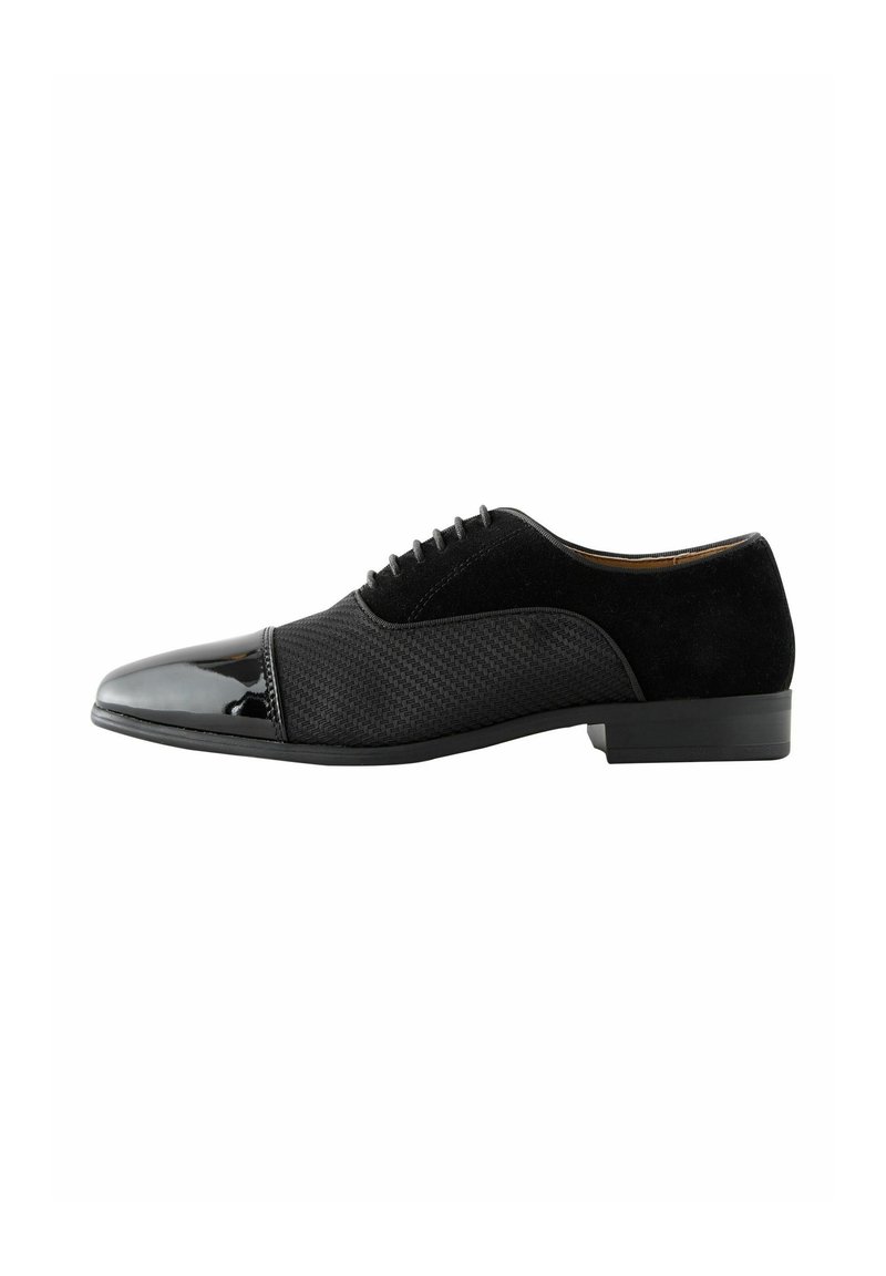 Schwarze Herrenschuhe mit glänzendem Zehenteil, strukturiertem Mittelteil, Wildlederabsatz und Schnürdesign vor weißem Hintergrund.