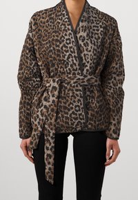 Leopardmönstrad omslagjacka i nyanser av brunt och svart, med bälte i midjan och kviltad textur med kontrasterande svart kant.