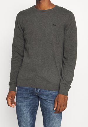 Pull gris à col rond avec manches longues, finitions côtelées aux poignets et à l'ourlet, fabriqué en tissu doux. Il présente un petit logo sur la poitrine. Associé à un jean bleu.