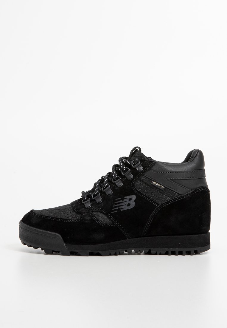 Schwarze Wanderschuhe aus Wildleder und synthetischen Materialien, mit einer strukturierten Oberfläche, runden Schnürsenkeln und einer robusten Sohle für guten Halt.