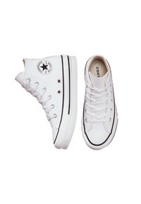 Baltos odinės Converse sportbačiai su juodais akcentais, guminiais padais ir skylutėmis; vienas aukštas ir vienas žemas modelis.