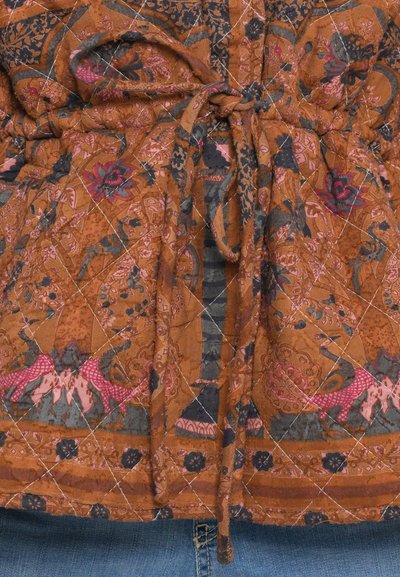 Bruin stoffen stof met bloemmotief en contrasterende blauwe accenten, met een getailleerde tailleband en een doorgestikte textuur.