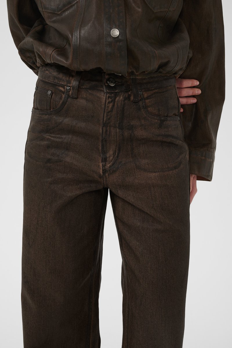 Brown denim jeans with a straight leg fit, featuring a classic five-pocket design and subtle texture variations. Button-fly closure.