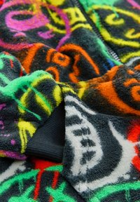 Fleece zip-up jacket with vibrant multicolored abstract patterns. Features a textured surface and ribbed cuffs in dark gray.