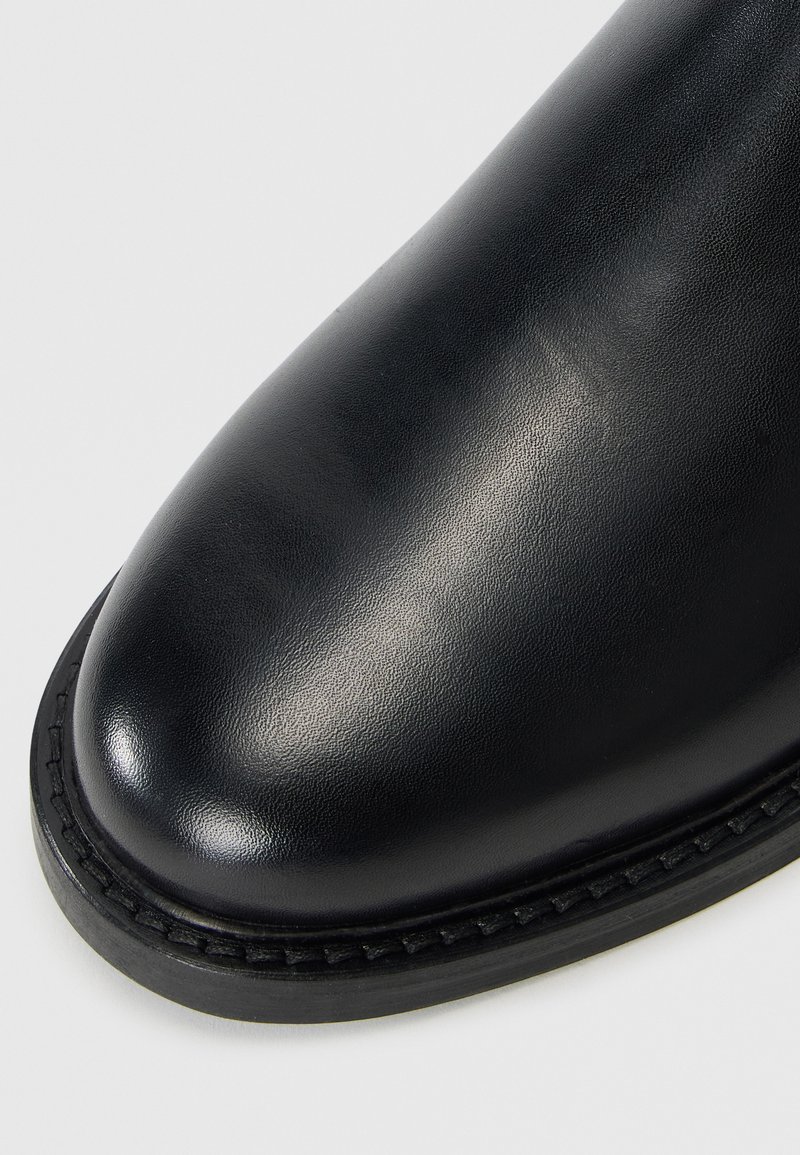 Schwarze Lederstiefel mit runder Zehenpartie, glatter Textur und kontrastierendem, genähtem Ledersohlen. Standardhöhe ohne sichtbare Beschläge.