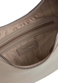 Unutrašnjost bež torbice prikazuje zip džep i tkaninu s ušivenom markicom "Pepe Jeans London."