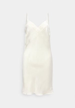 Φόρεμα ολίσθησης από λευκό σατέν με λεπτές τιράντες και λαιμόκοψη με κυματιστό σχέδιο, παρουσιάζεται σε απλό φωτεινό γκρι φόντο.