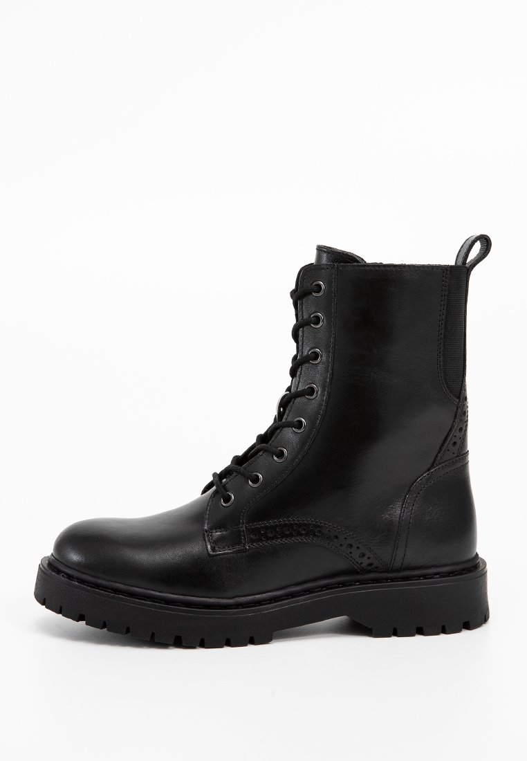 Schwarze Leder-Stiefelette mit runder Spitze, Schnürverschluss und Broguemustern. Verfügt über eine robuste Gummisohle mit leichtem Profil.
