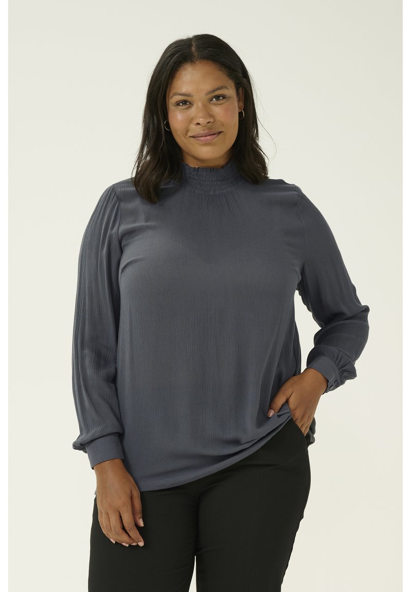 Blusa grigio scuro con maniche lunghe, scollatura arricciata, maniche plissettate e polsini con bottoni, realizzata in un tessuto leggero e morbido.
