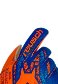 Guantes de portero con esquema de color naranja y azul. Presentan una palma texturizada, patrones hexagonales y una correa de pulgar reforzada. Marca "Reusch" visible.