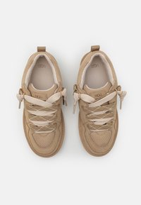 Baskets de sport beiges avec des empeignes en maille et en daim, bout rond et lacets plats. Possède des accents texturés et une semelle intérieure rembourrée.
