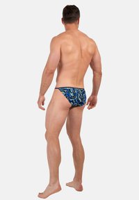 Bade-Shorts aus dehnbarem Stoff, mit einem blauen abstrakten Wellenmuster, einem tiefen Schnitt und minimaler Rückendeckung.