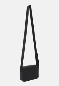 Borsa a tracolla nera realizzata in materiale testurizzato, caratterizzata da una forma rettangolare, chiusura con zip piatta e tracolla regolabile.