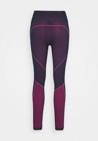 Hög midja leggings i mörklila och rosa. Har ett texturerat mönster och en slät yta med kontrasterande rosa sömmar längs sömmarna.