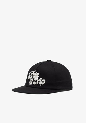 Gorra negra de tela con visera plana. En la parte frontal presenta un texto en blanco en negrita que dice "La vida es un viaje". Se puede ver un detalle de la parte superior redondeada.