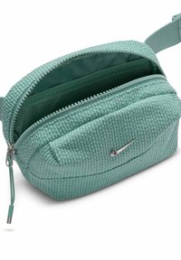 Small textured teal waist bag with silver Nike logo, open zipper revealing mesh inner pocket and adjustable strap.
