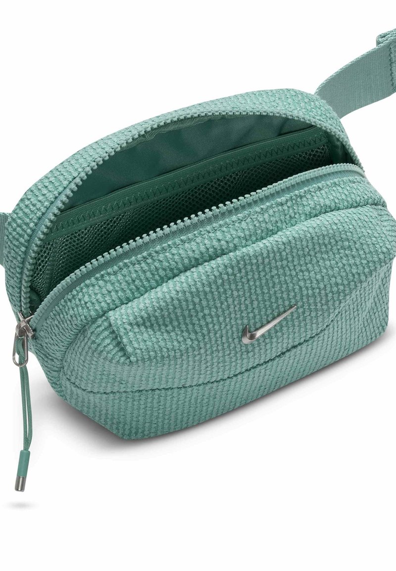 Kleine strukturierte türkisfarbene Hüfttasche mit silbernem Nike-Logo, offener Reißverschluss mit sichtbarem Netzinnentaschen und verstellbarem Trageriemen.