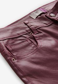 Bordeauxfarvede jeans med en glat tekstur, fem-pockets design og kontrasterende syninger. Udstyret med en metalknap og en label med teksten "Flare."