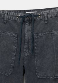 Harmaat farkkushortsit, joissa on naru- ja vetoketjukiinnitys. Niissä on kaksi suurta etutaskua ja teksturoitu kangaspinta.