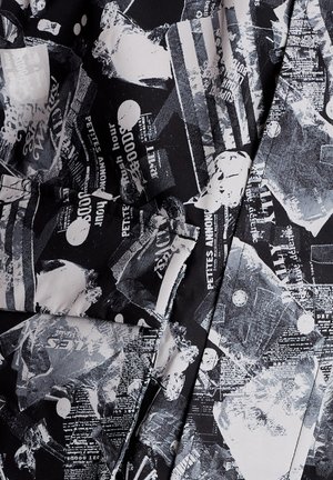 Sort og hvidt stof med abstrakt, lagdelt avis- og teksttryk, inklusive sætninger som "PETITES ANNONCES" og "good hour."