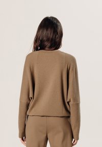 Bruine oversized trui met geribbelde manchetten, gemaakt van een zachte stof, voorzien van een ronde hals en een relaxte pasvorm.