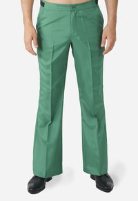 Pantalons larges verts au toucher lisse, dotés d'un pli avant, d'une fermeture à bouton et de détails de poche au dos, associés à des chaussures noires.