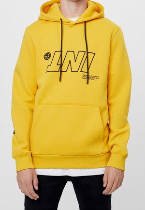 Yellow hoodie with black text, featuring a front pocket and adjustable drawstrings. Made from soft fabric, with ribbed cuffs and hem.