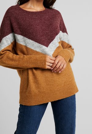 Pull en tricot de couleur bordeaux, gris et moutarde avec un motif en chevrons, des poignets côtelés et un large col, fabriqué en fil doux.