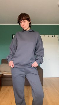 Grijze pullover hoodie met een relaxte pasvorm, verlaagde schouders en een kangaroo-zak, gecombineerd met bijpassende grijze joggerbroek, medium textuur.