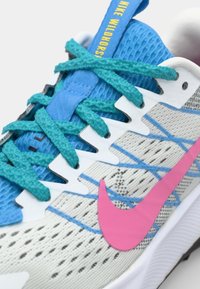 Nike Wildhorse running shoe features a blue mesh upper with textured gray accents, turquoise laces, and a pink Swoosh logo.