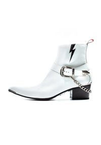 White ankle boot made of smooth leather with pointed toe, black lightning bolt accent, silver buckle, and chain detail around the heel.