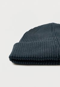 Căciulă tricotată albastru închis, confecționată din material moale, cu textură striată și manșetă pliabilă pentru o fixare confortabilă.